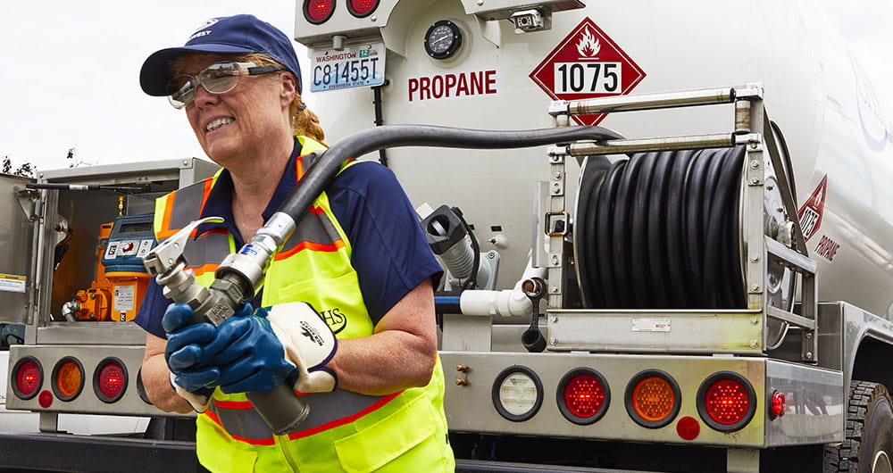一个女人从一辆丙烷卡车后面拖着一根软管