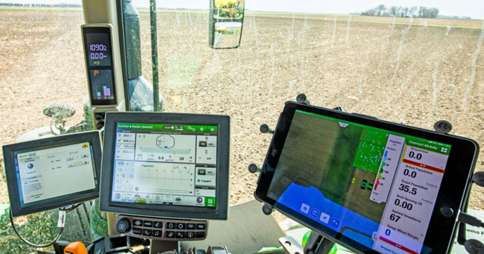 Inside a tractor looking at screens displaying data from precision agriculture software 