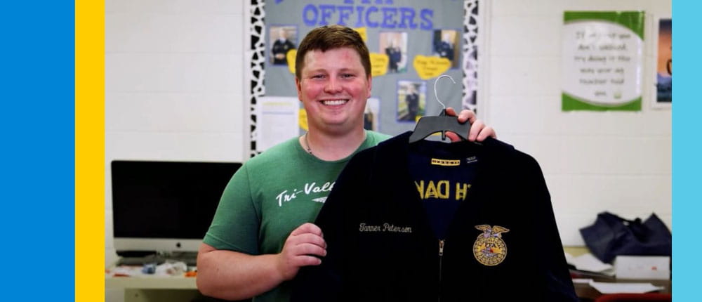 Tanner Peterson holds up the FFA jacket he earned when he was a student
