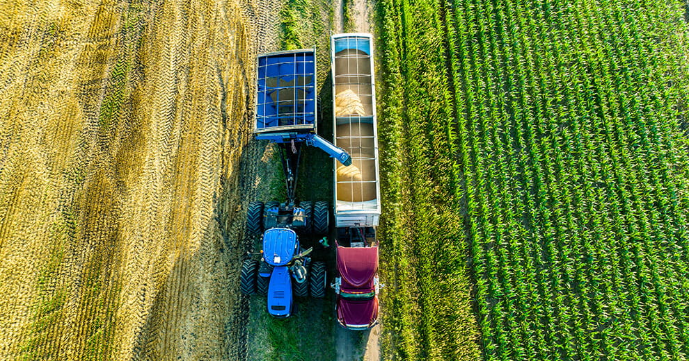 Semi truck being loaded by combine during harvesting of a field