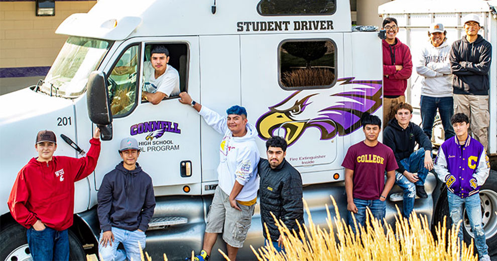 High school students standing in front of a semi cab