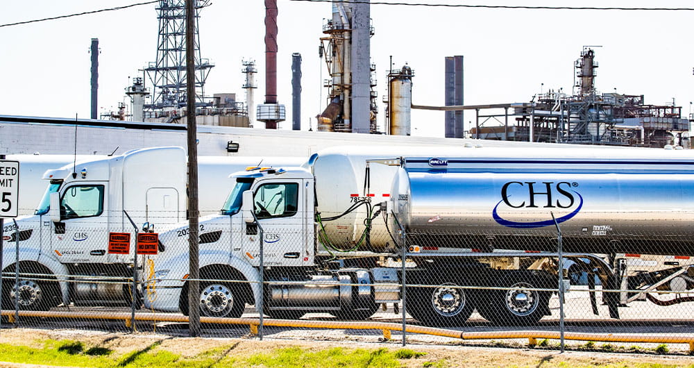 CHS fuel tanker trucks with a refinery in the far background