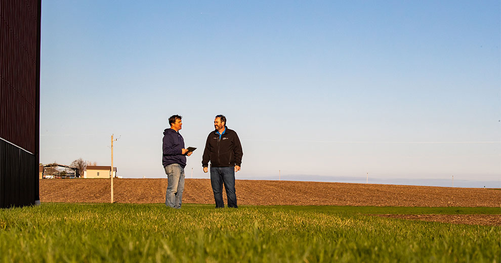 Two men talking beside an open field
