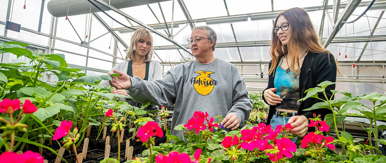 Teacher and students looking at flowers inside a greenhouse