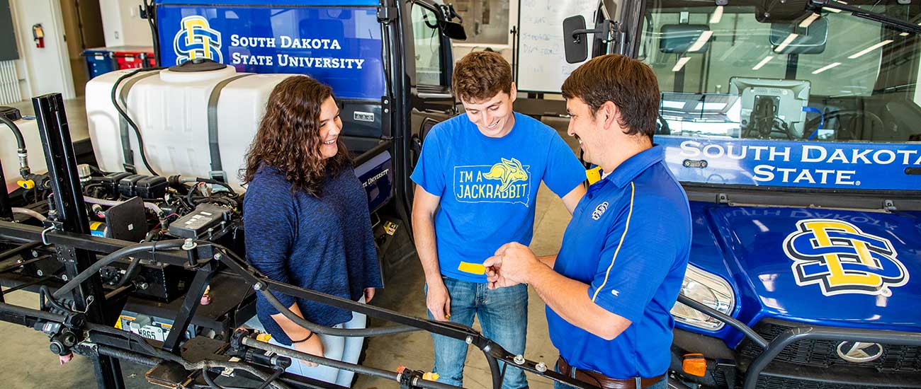 SDSU students and instructor with branded ag equipment 