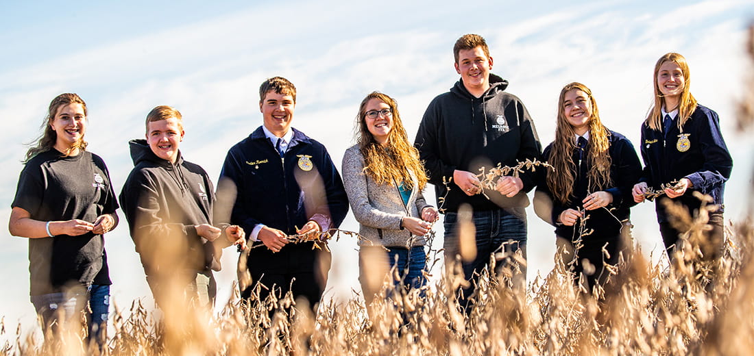 FFA students standing in field holding wheat stalks