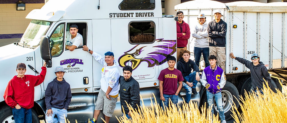 A group of high-school students poses next to a truck that says Student Driver on the side