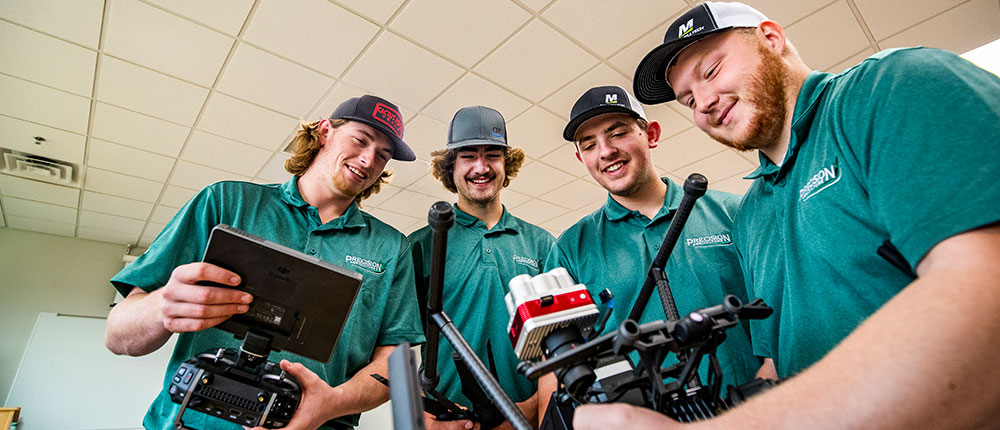 Four college students gathered around a drone inside a classroom