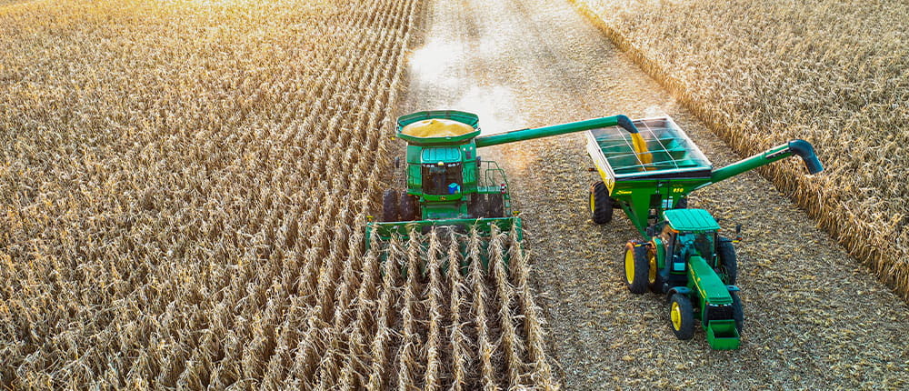 A tractor and combine harvester harvesting crops from a field.