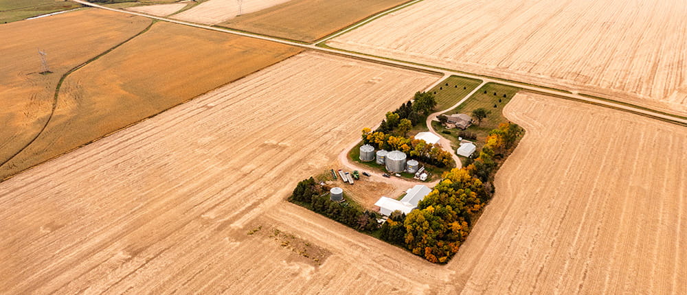 Aerial photo of a farmstead with fields, grain bins, house, machine shed and equipment