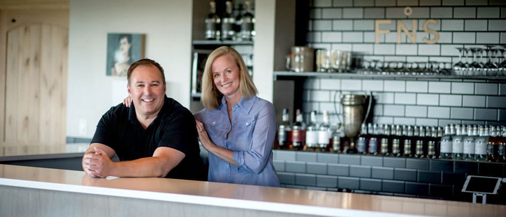 Owners Cheri Reese and Michael Swanson standing behind the bar at Far North Spirits