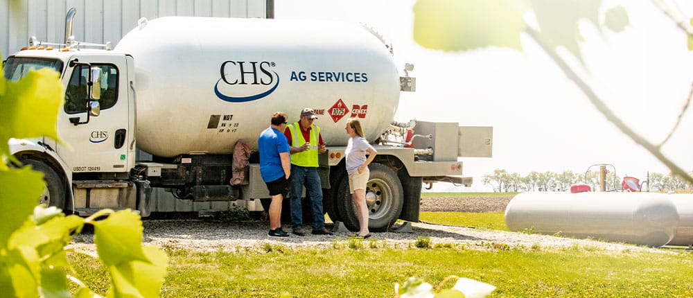 Three people standing by propane truck