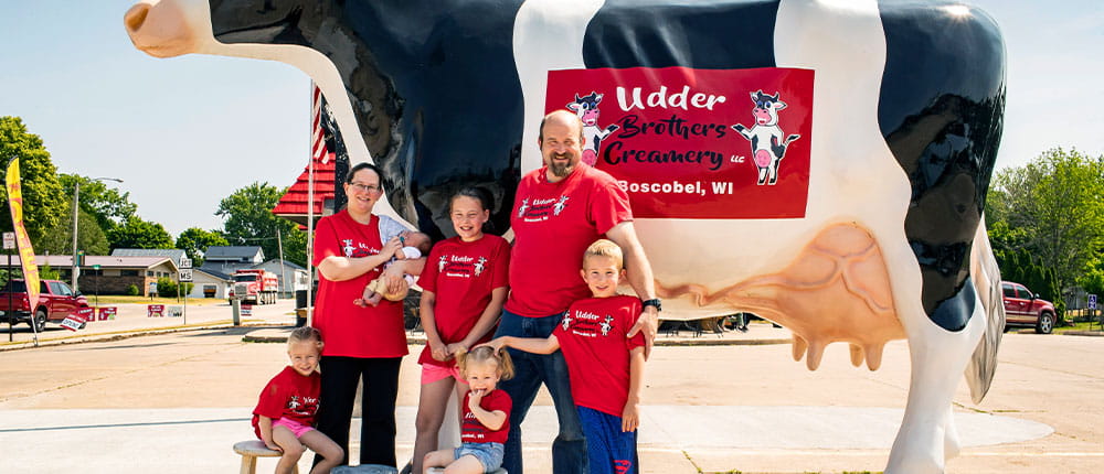 Family standing in front of giant cow