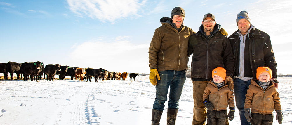 Richard Stadheim stands in a snow-covered cattle field with his sons, Garrett and Bennett, and Bennett’s young twin boys.