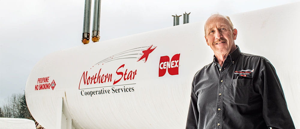 Man standing next to bulk propane tank branded with Northern Star Cooperative Services and Cenex logos