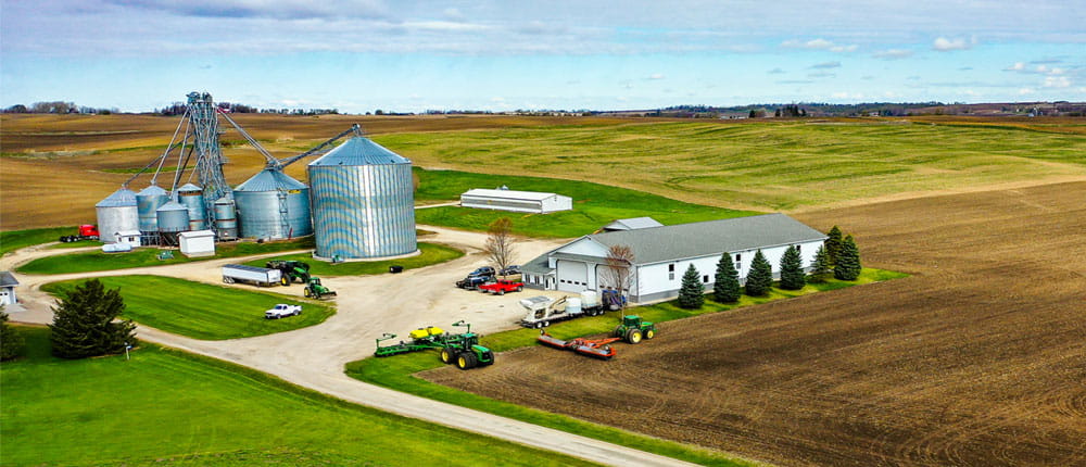 An aerial photo of a farm in early spring, with a grain bin and farm equipment.