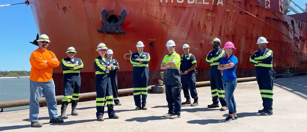Group of workers at Myrtle-Grove Terminal standing in front of a large ship. 