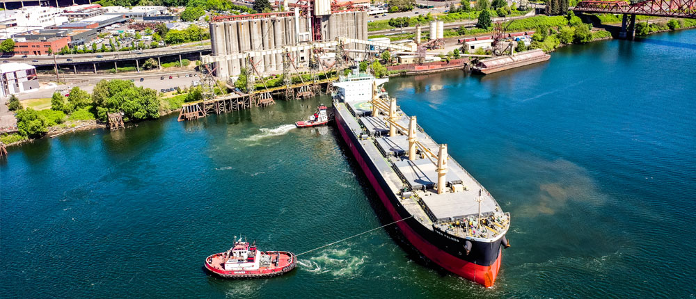 Tugboat helps ship leave international shipping port.