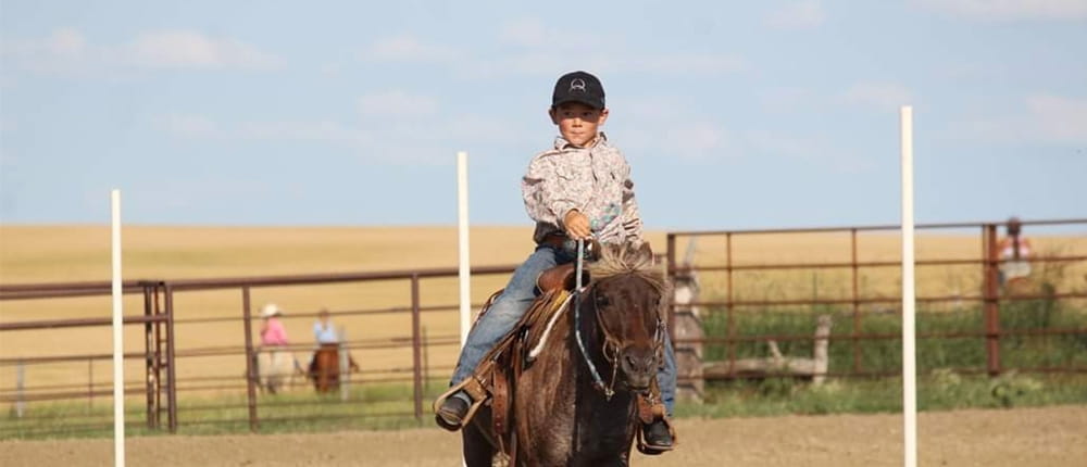 boy rides horse in rodeo ring