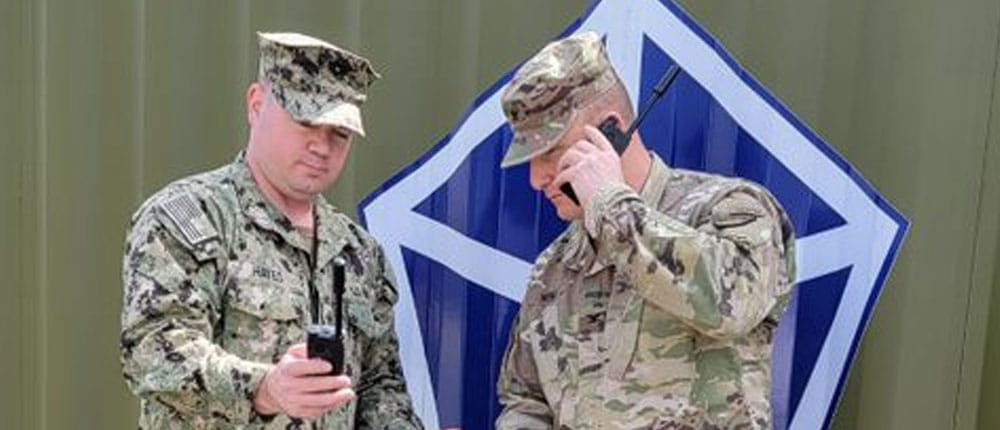 Two uniformed men talk on radios  