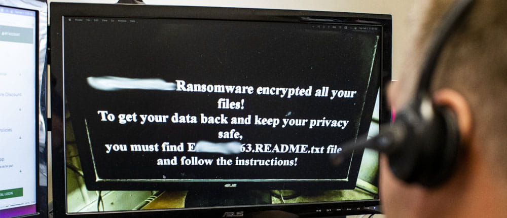  A man reads a ransomeware message on his computer monitor.