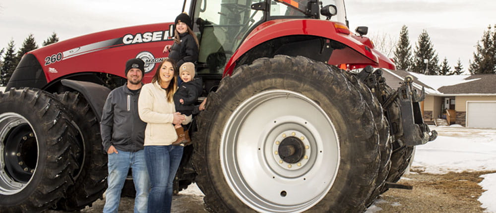 A family stands in front of their tractor.