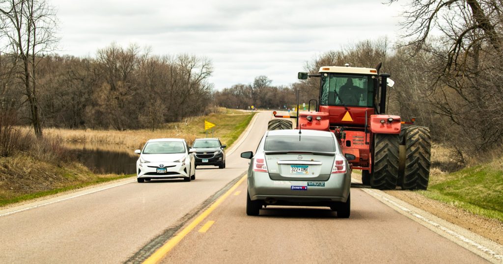 Cars safely passing a tractor driving on the road