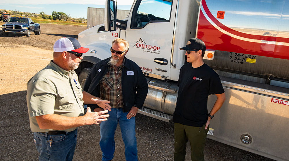 Three men by a fuel truck