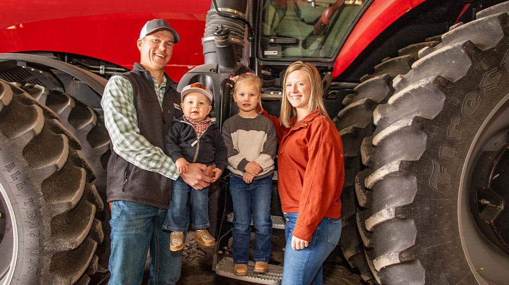 Man, woman, and two young children next to a tractor