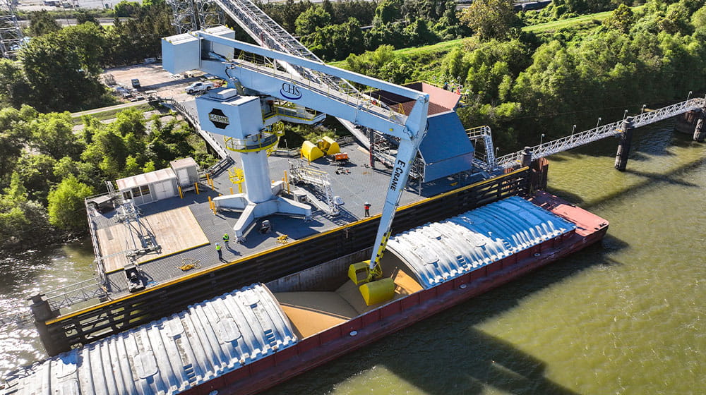 Crane unloading a barge filled with soybean meal