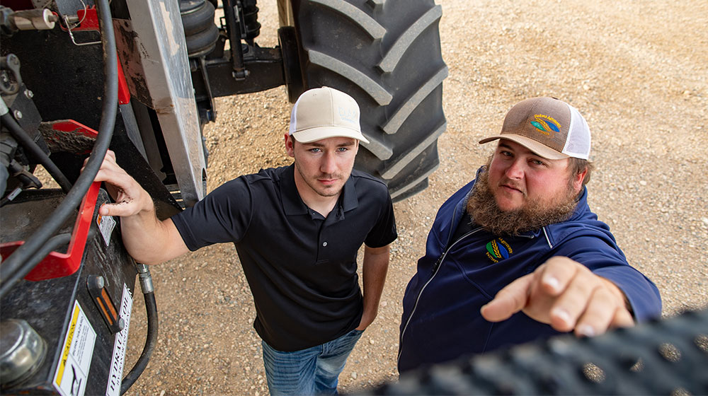 Two men standing by farm equipment.